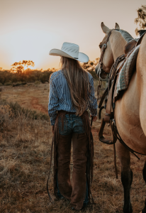 Woman with long blond hair and her horse facing away