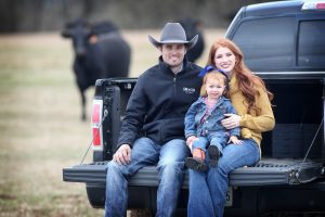 Hamish and Courtney Harley sitting on the tailgate of their truck with their daughter.