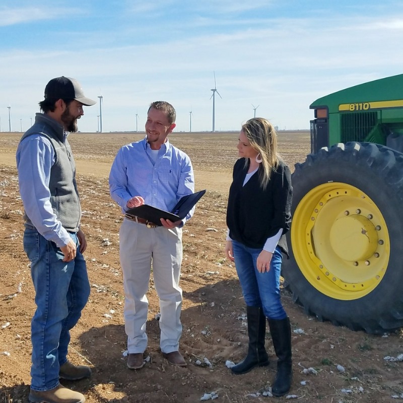 Jason Jones, Credit Office President, AgTrust Farm Credit, Abilene and Sweetwater, Texas. talking with customers in field next to a tractor.
