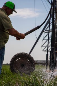 Man adjusting the nozzle of an irrigation pivot in a field
