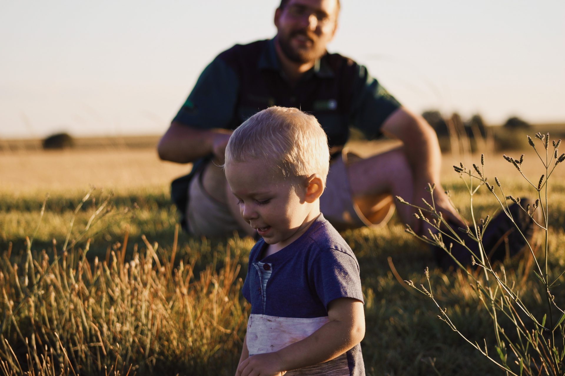 Baby and father sitting in the grass. AgTrust Farm Credit provides loans for generations of family farms and ranches.