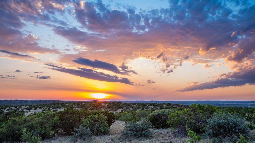 Sun setting on ranch land. AgTrust Farm Credit provides loans for farm equipment and improvements.