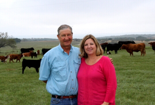 Benton and Linda Floerke at their place with cattle on pasture in the background.