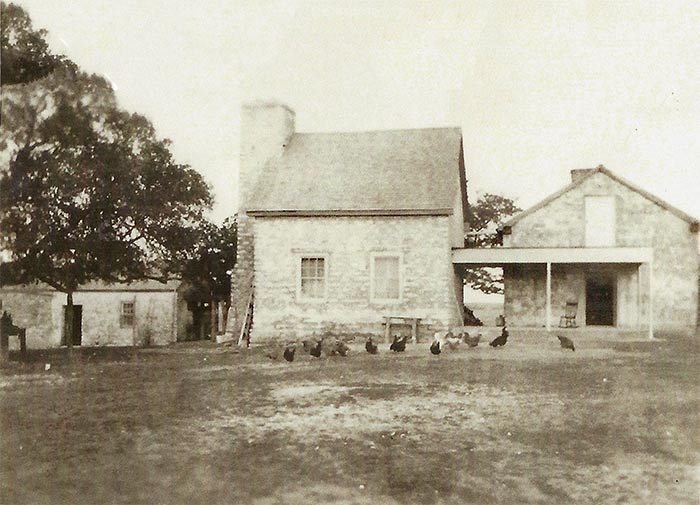 Historic stone home photo with chickens in the yard.