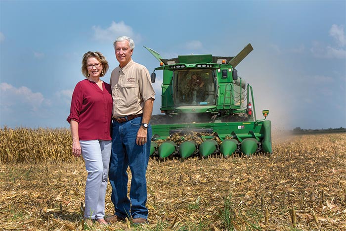 John and Natasha Sawyer in field with combine in the background.