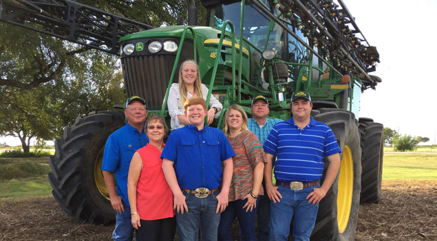Family standing in front of John Deere tractor.