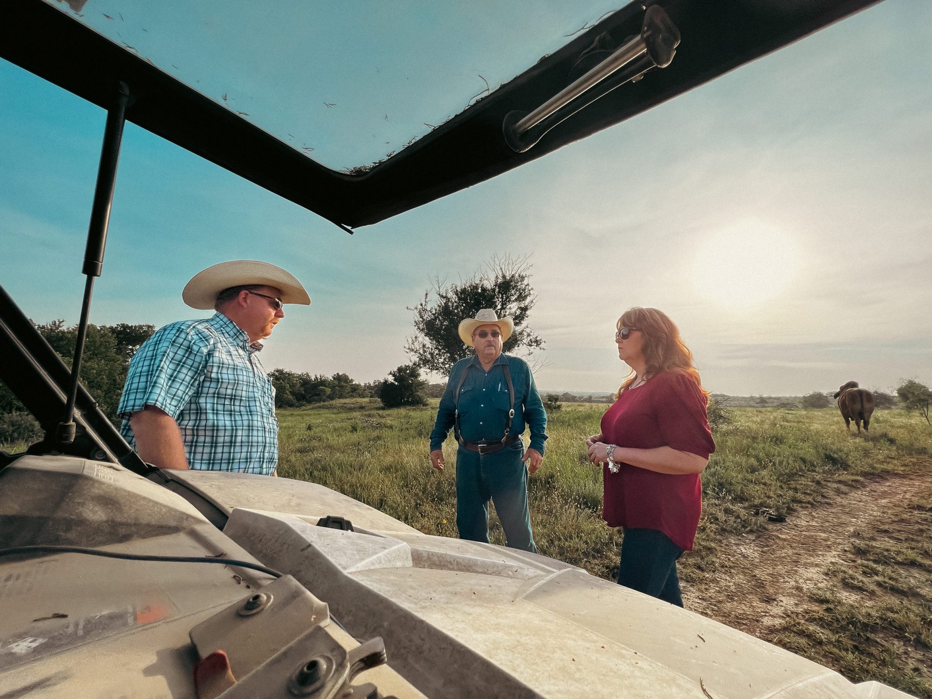 Three ranchers talking outdoors.
